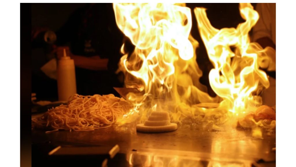 grill of noodles, onions, meat on fire at Japaneses restaurant
