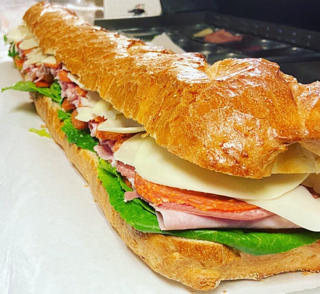 long submarine sandwich with salami, turkey, provolone cheese and lettuce
