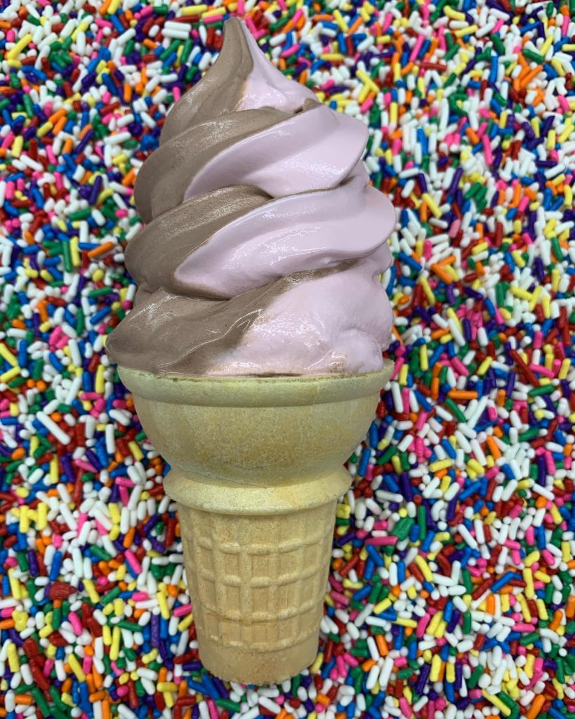 chocolate and raspberry swirl ice cream cone on a background of sprinkles