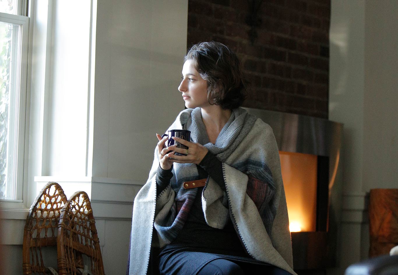 Woman sitting by the fire with a cup of coffee