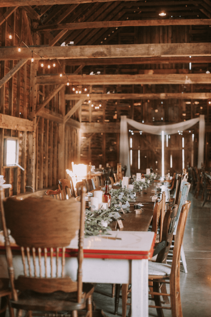 Long rectangular table with decorate table scape inside a barn