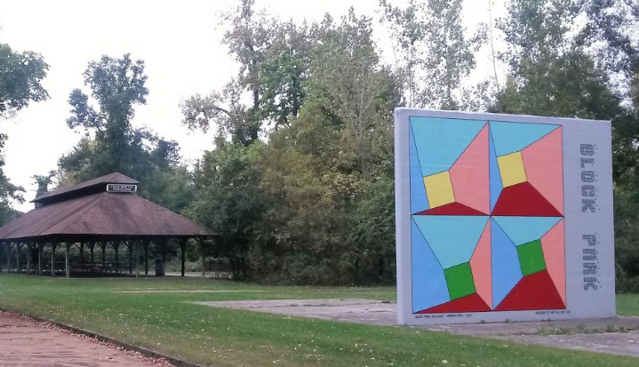 covered pavilion in a park with art in front of it