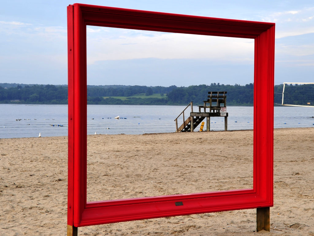 red art frame that showcases the Kingston Beach and Hudson River behind it