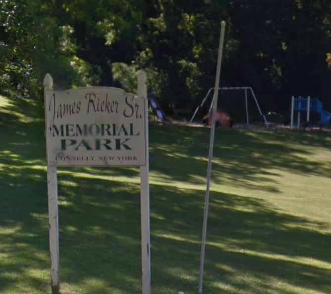 park with white wooden sign and playground equipment