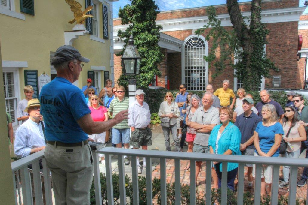 tour guide on white porch speaking to visitors