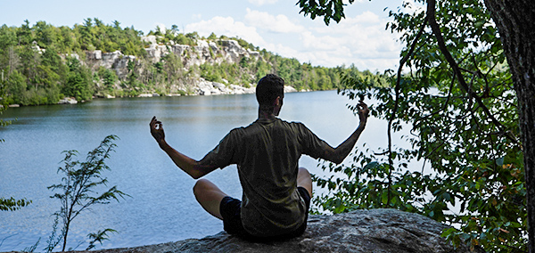 man doing yoga pose overlooking water
