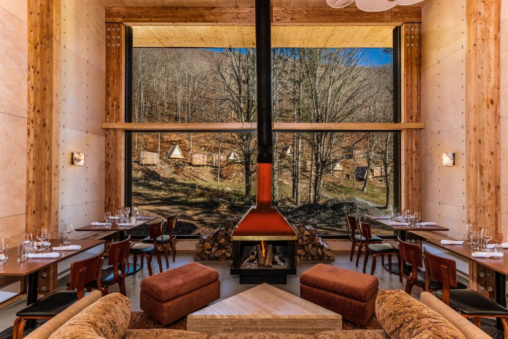 woodburning stove in middle of dining area with view of woods