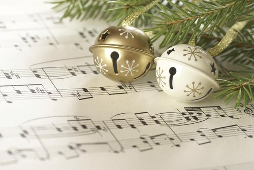 gold and white jingle bells sitting on top of sheet music