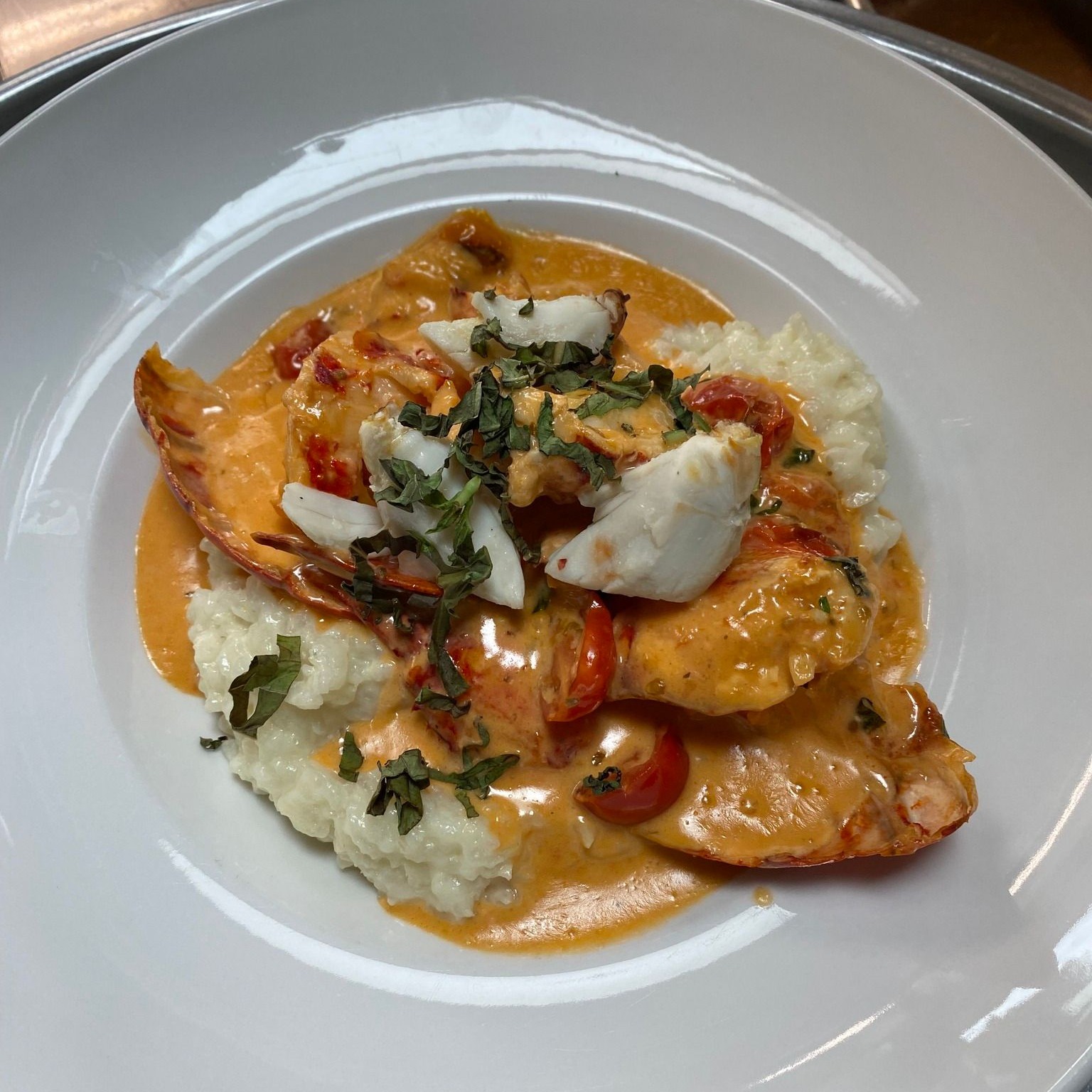 white plate of seafood, tomato sauce, and grits