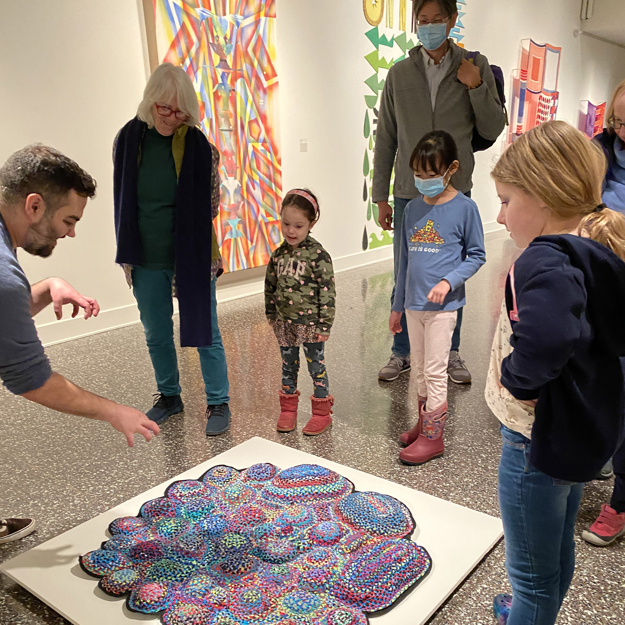 artist explaining a mosaic artwork to children and their families