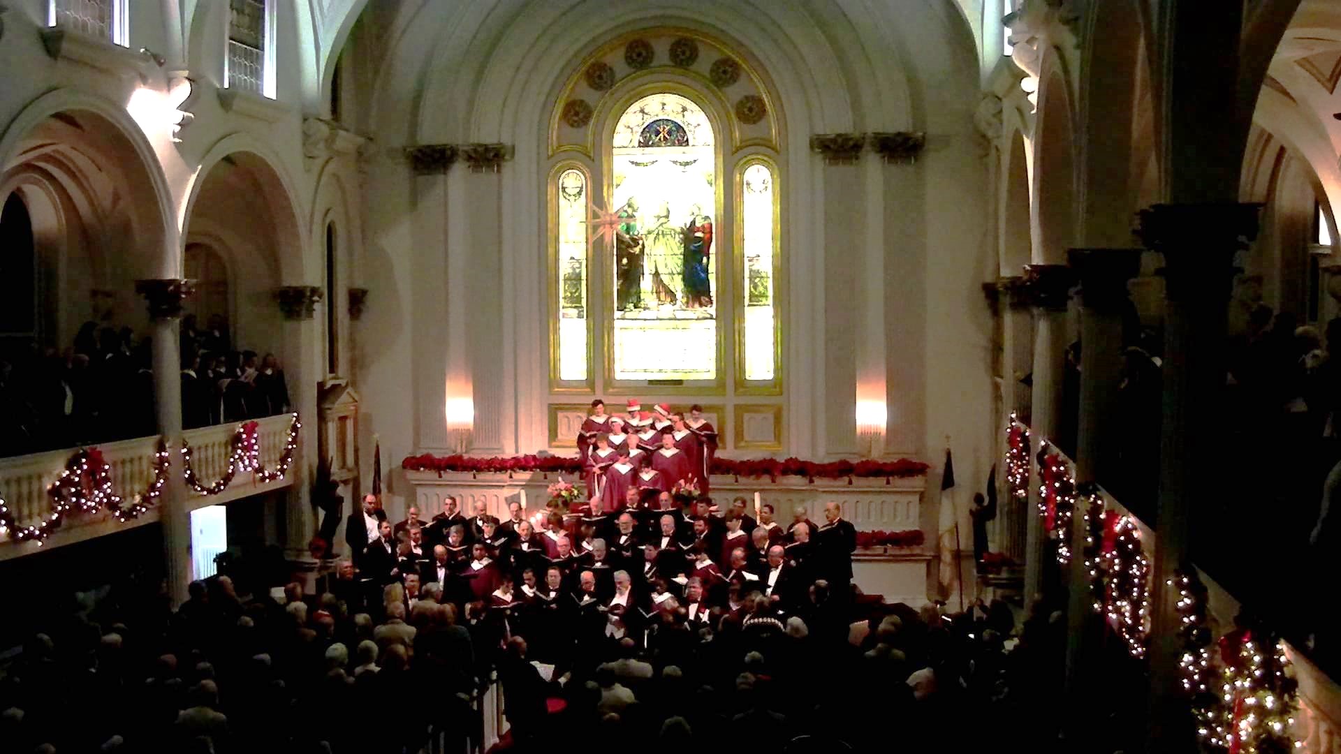 choirs singing at the front of a church decorated for Christmas
