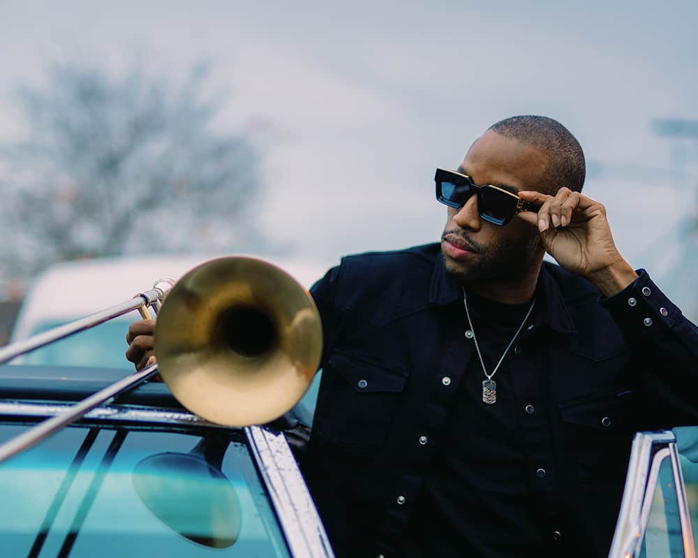 Trombone Shorty stepping out of car with his trombone in hand