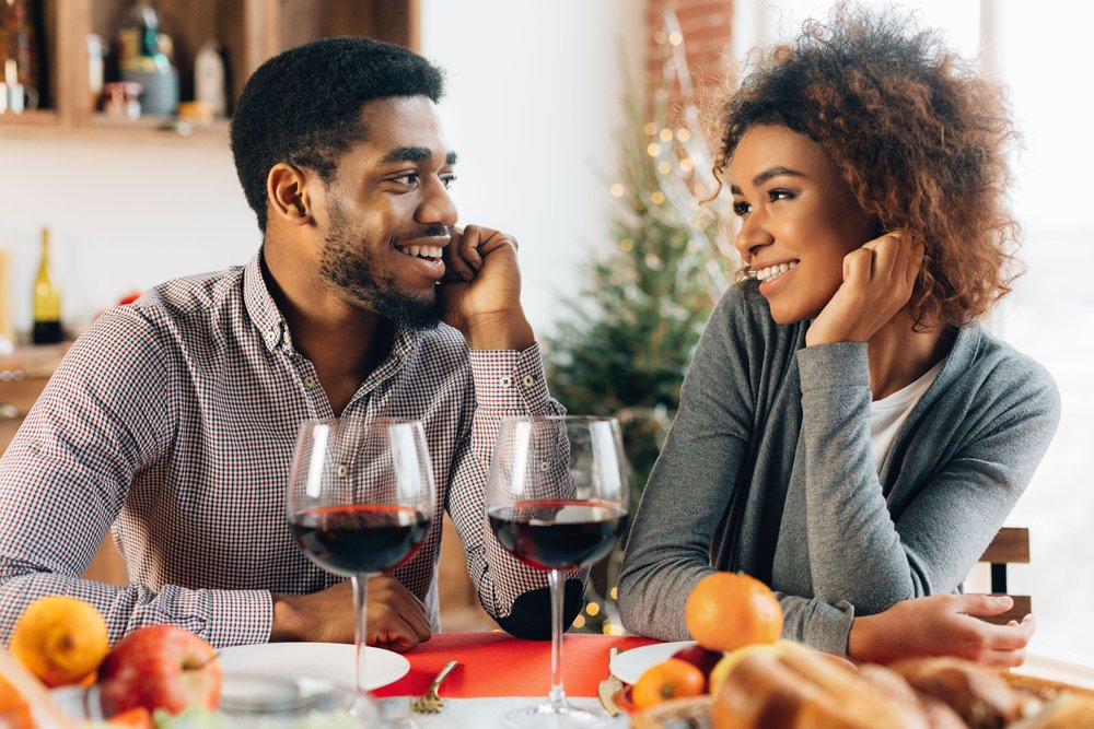 couple gazing at each other at a dinner table with glasses of red wine