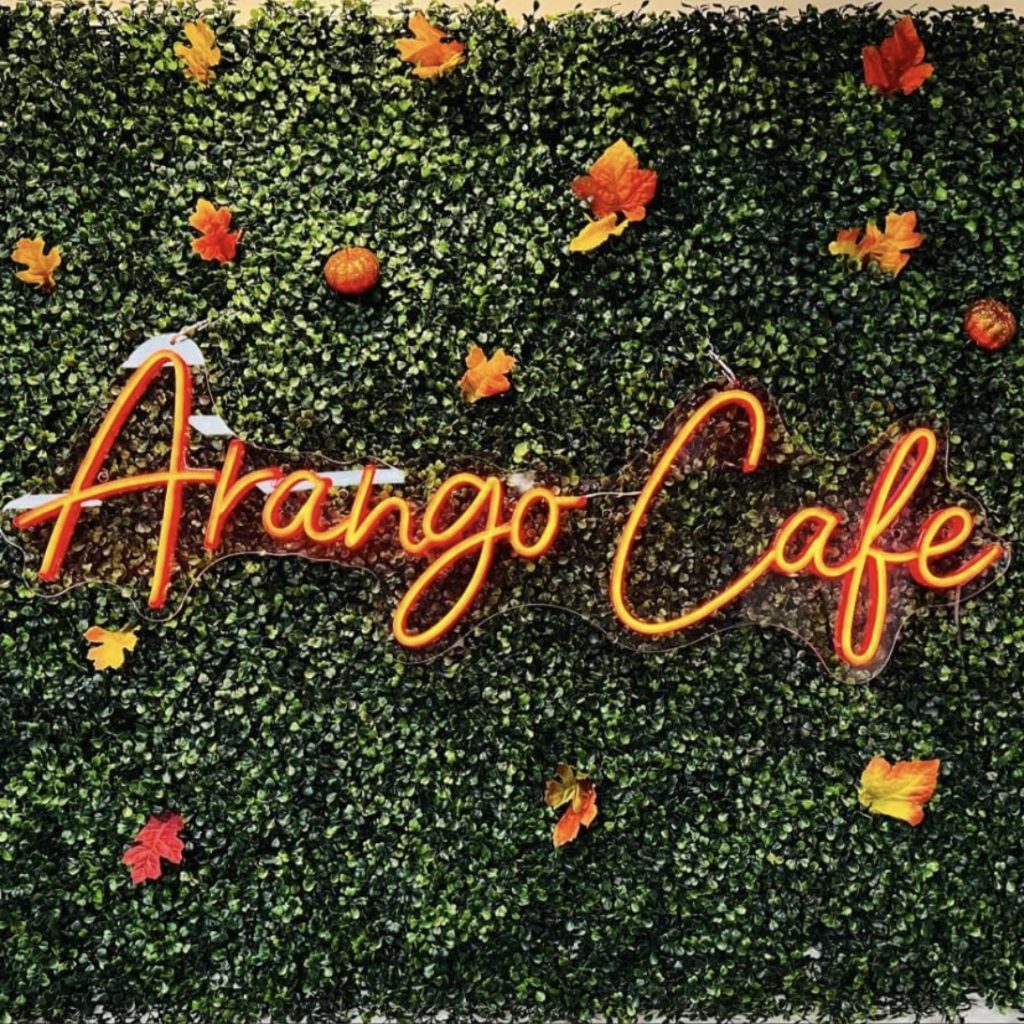 wall of greenery with orange neon sign that reads Arango Cafe