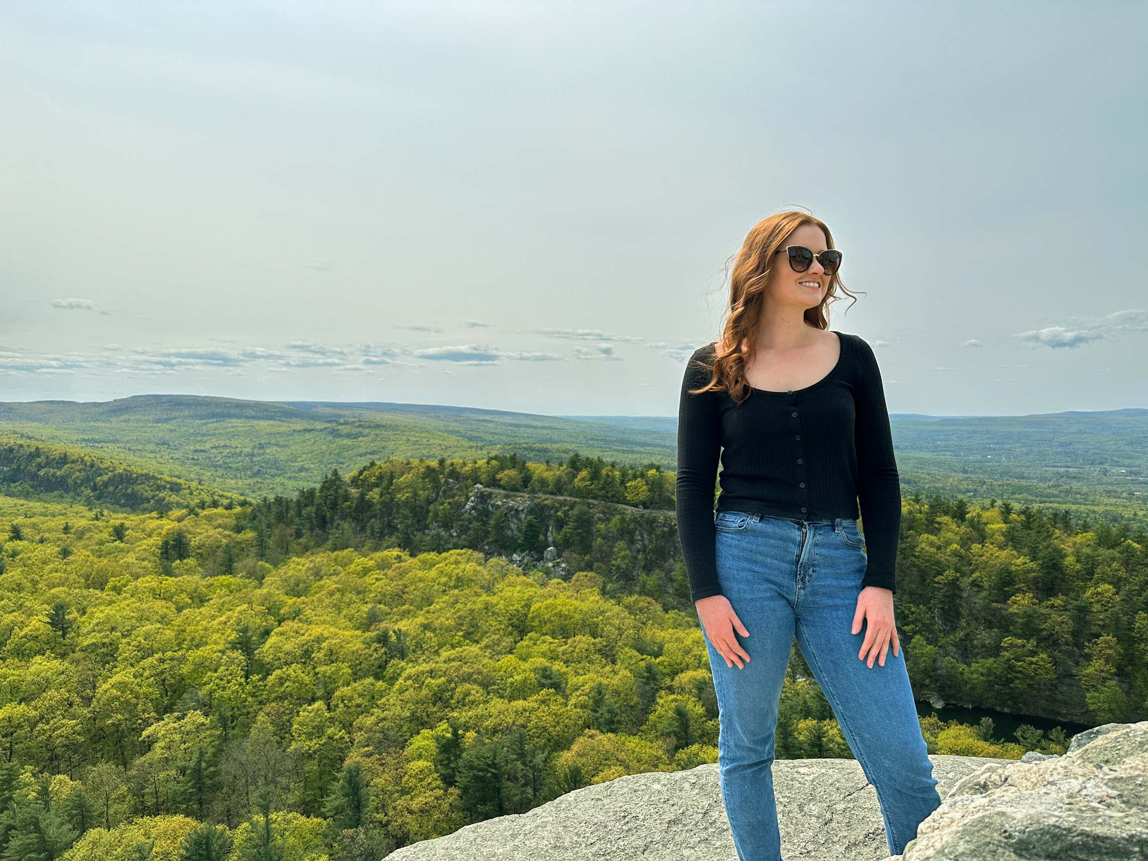 Woman standing on top of cliff overlooking mountain side