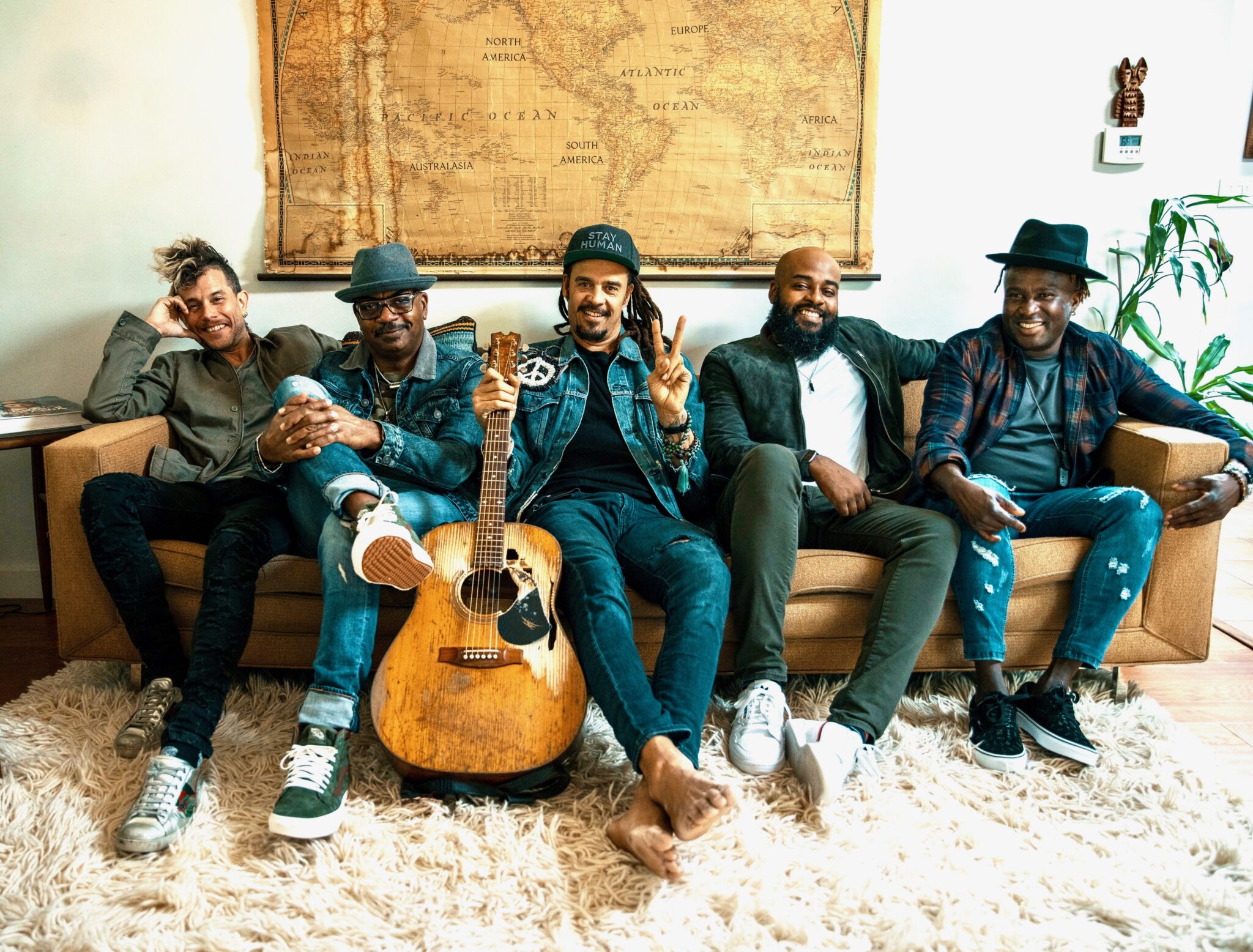 Michael Franti & Spearhead sitting on a couch smiling