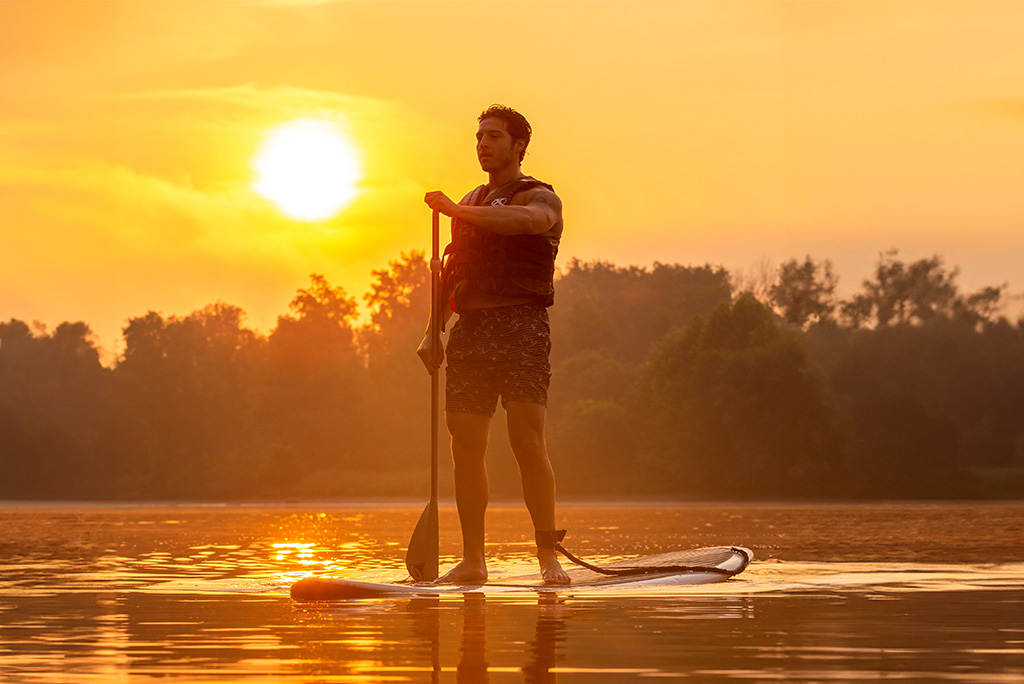 man on paddle board with sunset