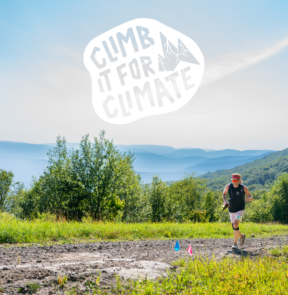 Runner in athletic gear on mountain trail with 'Climb It For Climate' text and green hills in the background.